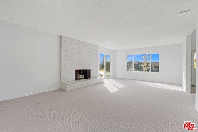 unfurnished living room with a textured ceiling, a large fireplace, and light carpet