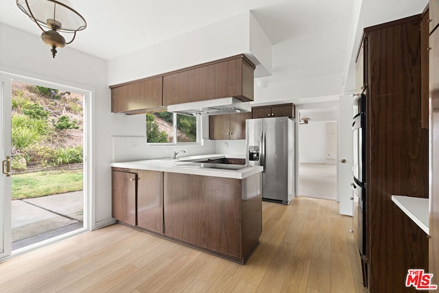 kitchen with plenty of natural light, kitchen peninsula, light hardwood / wood-style flooring, and stainless steel refrigerator with ice dispenser