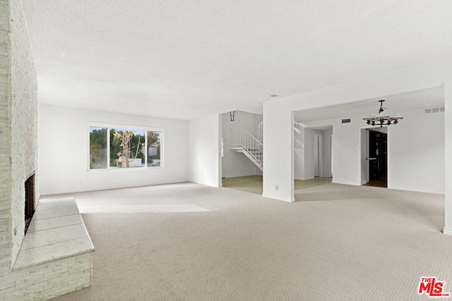 unfurnished living room with light carpet, a textured ceiling, and a fireplace