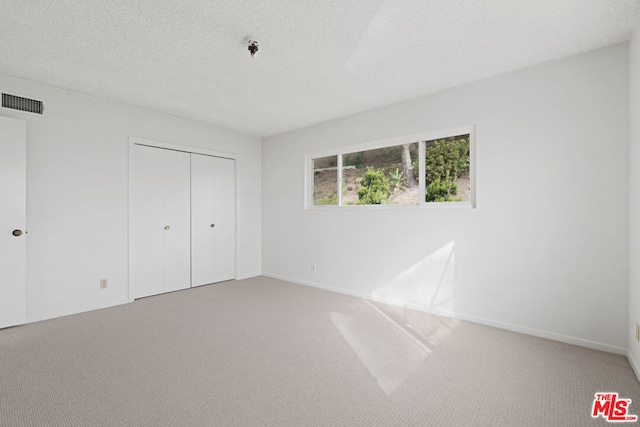 unfurnished bedroom with carpet flooring, a textured ceiling, and a closet