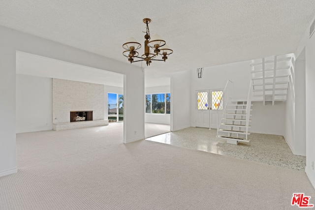 unfurnished living room with a fireplace, a textured ceiling, and an inviting chandelier