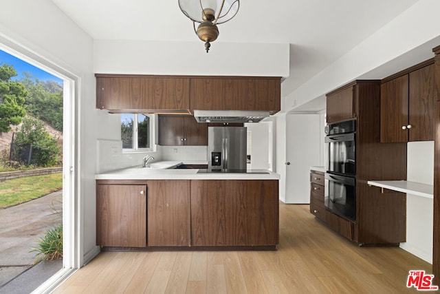 kitchen with stainless steel refrigerator with ice dispenser, double oven, kitchen peninsula, light hardwood / wood-style floors, and dark brown cabinets