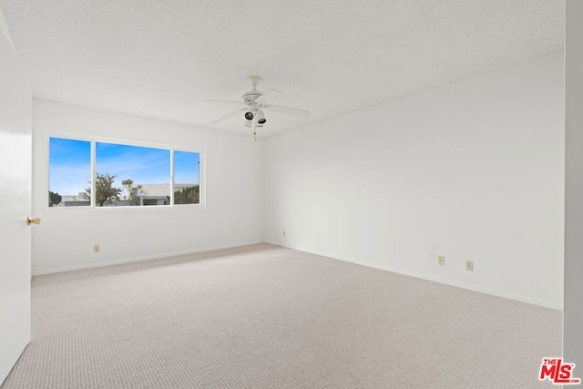 carpeted spare room featuring ceiling fan and a textured ceiling