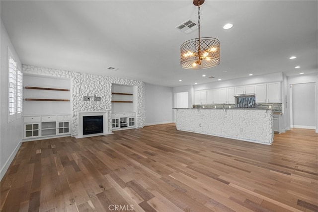 unfurnished living room with a chandelier and light wood-type flooring