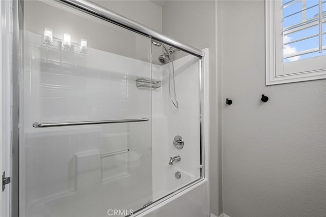 bathroom with bath / shower combo with glass door