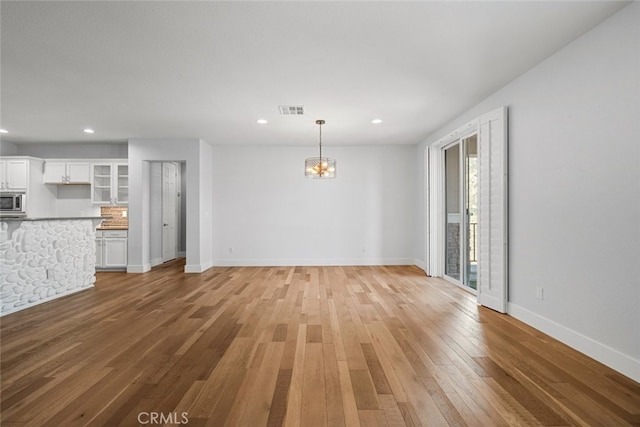 unfurnished living room featuring hardwood / wood-style floors and an inviting chandelier