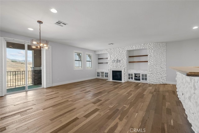 unfurnished living room with wood-type flooring and an inviting chandelier