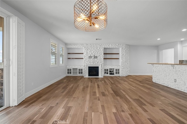 unfurnished living room with hardwood / wood-style floors and built in shelves