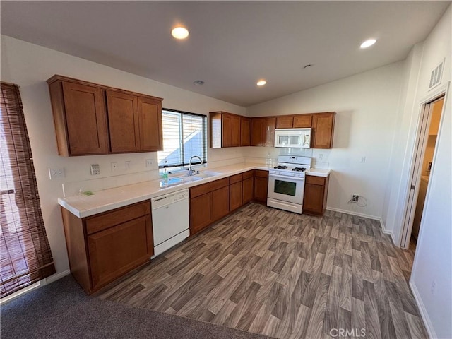 kitchen featuring white appliances, dark hardwood / wood-style floors, vaulted ceiling, and sink