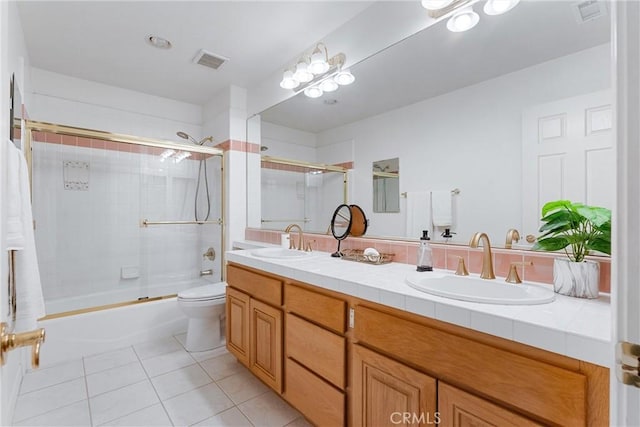 full bathroom featuring combined bath / shower with glass door, vanity, tile patterned flooring, and toilet