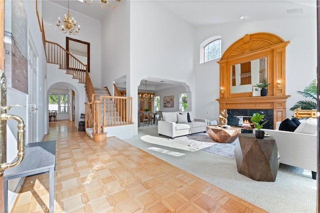 living room featuring a fireplace, plenty of natural light, a towering ceiling, and a chandelier