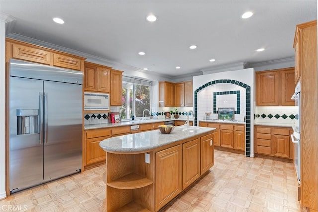 kitchen with built in appliances, a center island, sink, and tasteful backsplash