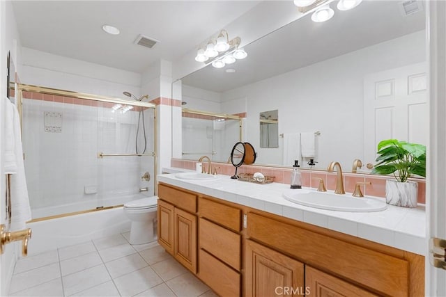 full bathroom featuring tile patterned floors, vanity, bath / shower combo with glass door, and toilet