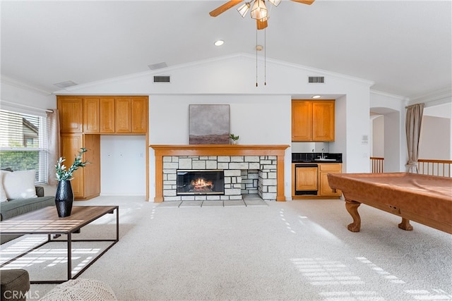 carpeted living room with a stone fireplace, lofted ceiling, crown molding, and pool table