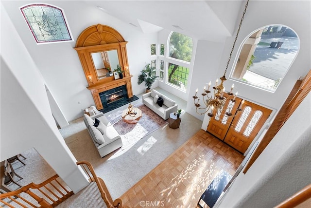 living room with carpet, a towering ceiling, and an inviting chandelier