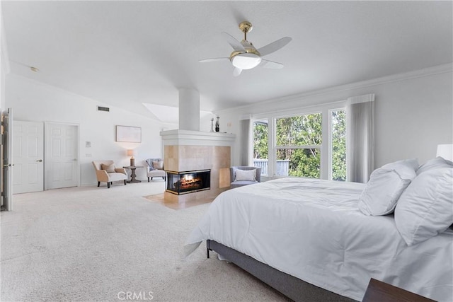 bedroom with ceiling fan, crown molding, carpet floors, lofted ceiling, and a tiled fireplace