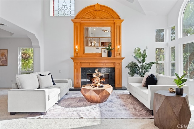 carpeted living room featuring a fireplace and high vaulted ceiling