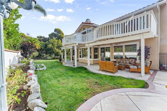 back of house featuring a lawn, an outdoor living space, a balcony, and a patio