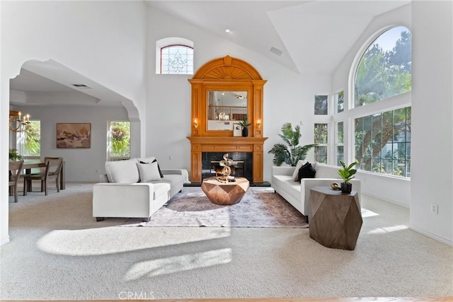 carpeted living room featuring high vaulted ceiling, a healthy amount of sunlight, and a notable chandelier