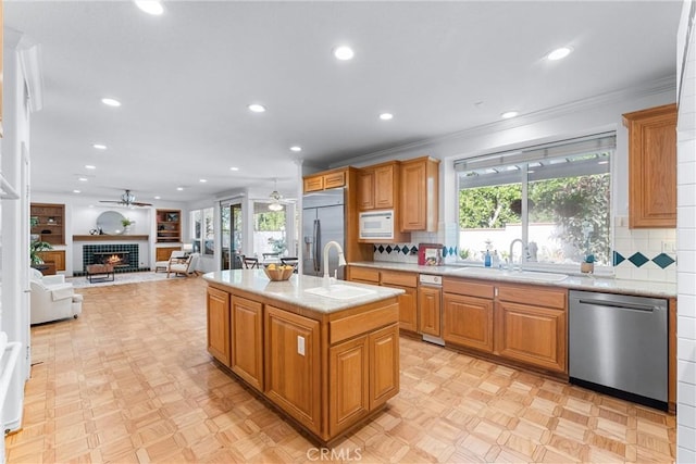 kitchen with built in appliances, sink, an island with sink, and a healthy amount of sunlight