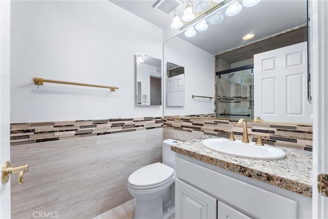 bathroom featuring an enclosed shower, vanity, toilet, and tile walls