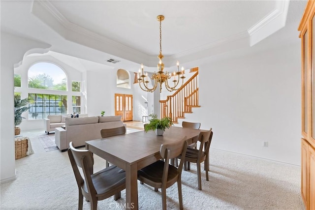 carpeted dining space featuring a raised ceiling, crown molding, and a chandelier