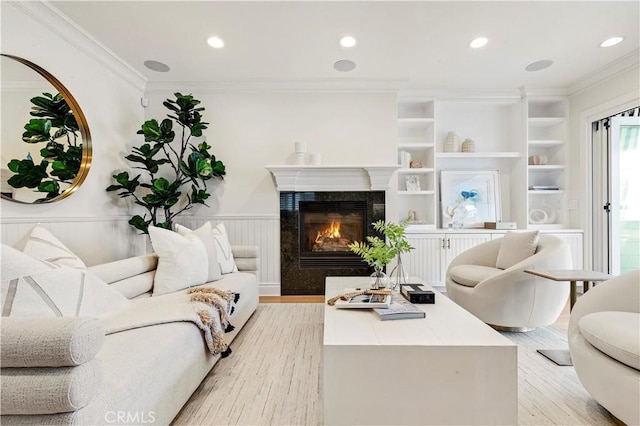 living room featuring a high end fireplace, light wood-type flooring, and ornamental molding