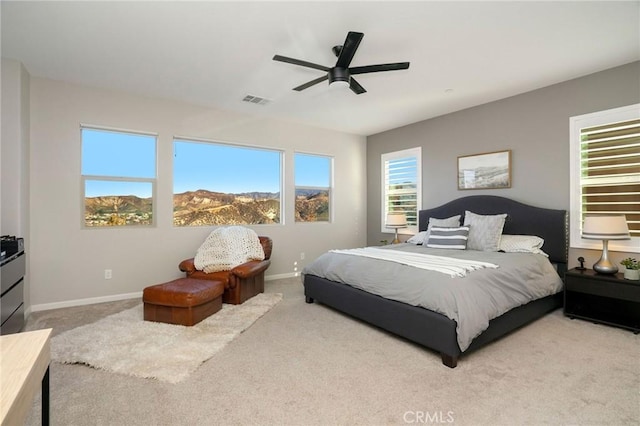 bedroom with light carpet, a mountain view, and ceiling fan