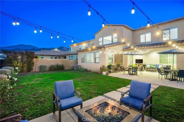 rear view of house with a patio area, a yard, and an outdoor living space with a fire pit