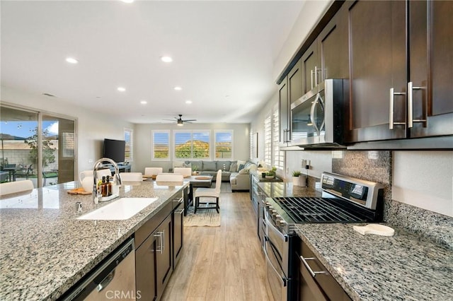 kitchen featuring light stone counters, dark brown cabinets, stainless steel appliances, sink, and light hardwood / wood-style floors