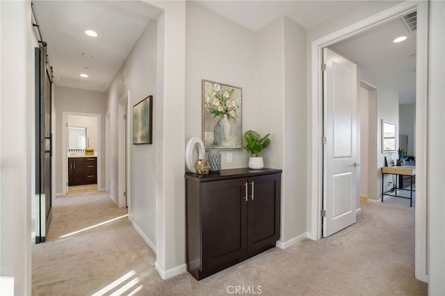 hallway featuring a barn door and light colored carpet