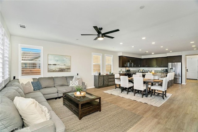 living room with ceiling fan and light hardwood / wood-style flooring