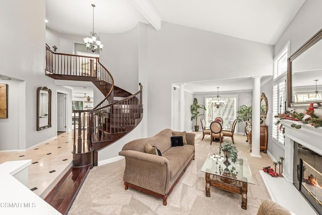 tiled living room with beam ceiling, a tile fireplace, a chandelier, and ornate columns