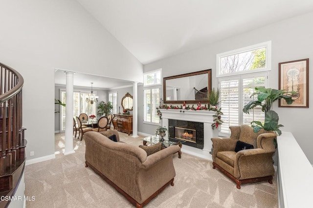 living room with decorative columns, a wealth of natural light, light colored carpet, and high vaulted ceiling