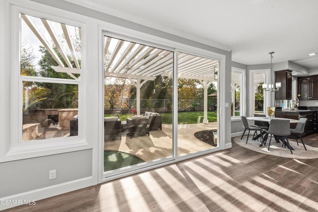 doorway to outside featuring an inviting chandelier, crown molding, sink, and hardwood / wood-style flooring