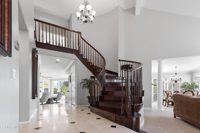 staircase featuring ceiling fan with notable chandelier, tile patterned floors, beam ceiling, and decorative columns