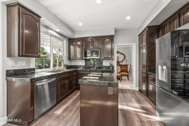 kitchen with sink, dark brown cabinets, stainless steel appliances, a center island, and wood-type flooring