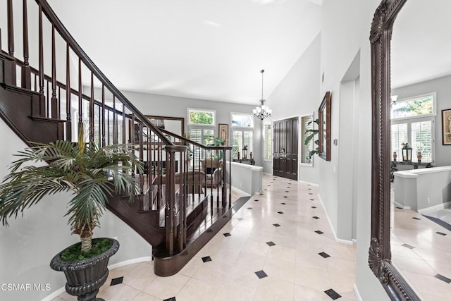 hall with light tile patterned floors, plenty of natural light, french doors, and a chandelier