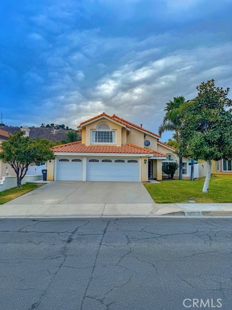 mediterranean / spanish-style house featuring a garage and a front lawn