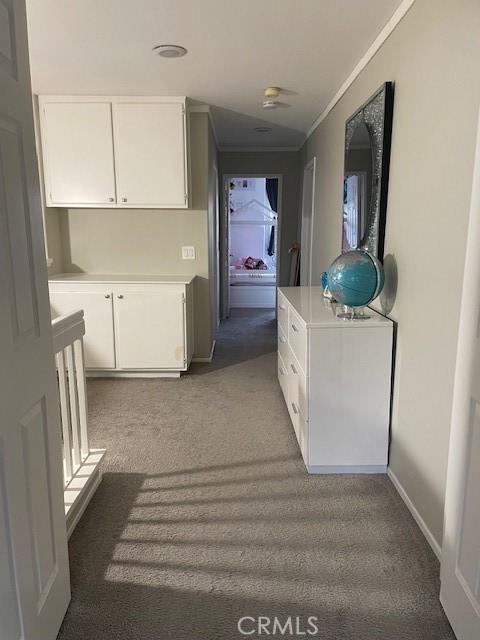 corridor featuring crown molding and dark colored carpet