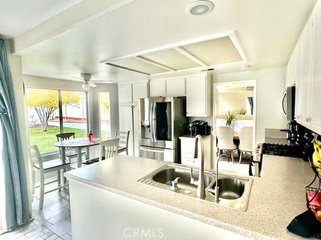 kitchen with appliances with stainless steel finishes, ceiling fan, sink, light tile patterned floors, and white cabinets