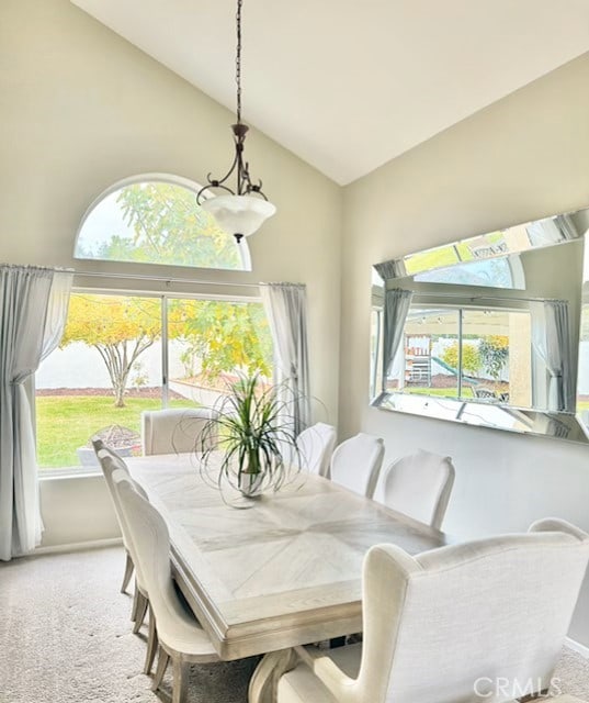 carpeted dining area featuring plenty of natural light and high vaulted ceiling