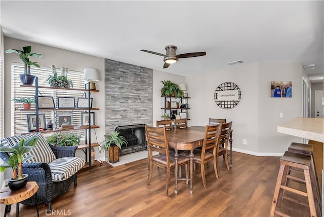 dining room featuring ceiling fan, dark hardwood / wood-style floors, and a fireplace