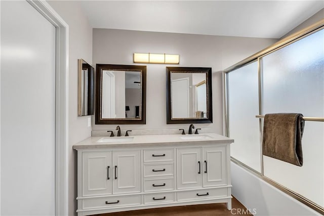 bathroom featuring enclosed tub / shower combo, wood-type flooring, and vanity