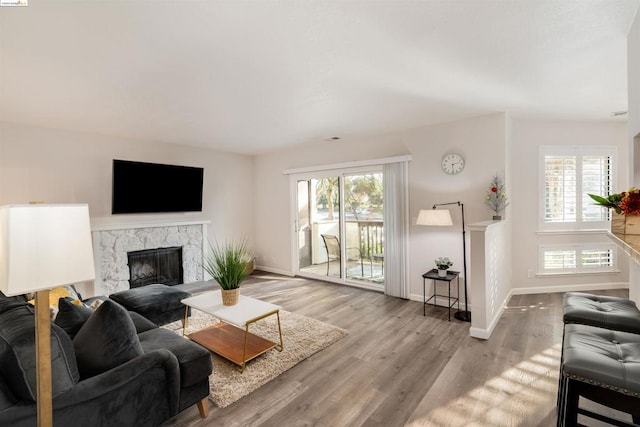 living room featuring light wood-type flooring and a high end fireplace