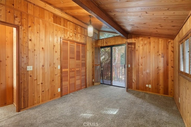 carpeted spare room with lofted ceiling with beams, wood ceiling, and wooden walls