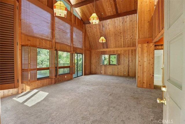 unfurnished living room featuring carpet, wood walls, and high vaulted ceiling