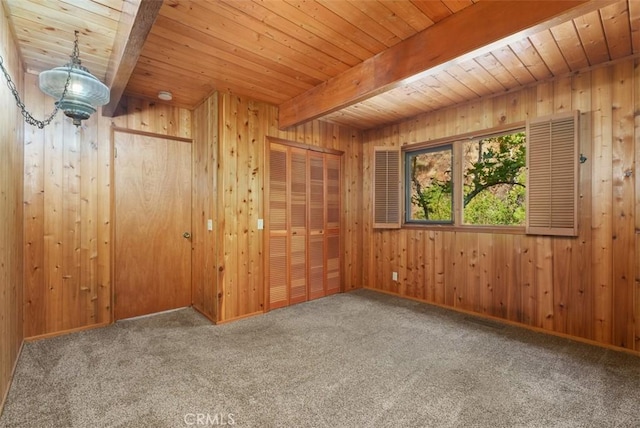 carpeted spare room with beamed ceiling, wooden ceiling, and wood walls