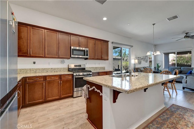 kitchen featuring light stone countertops, a kitchen breakfast bar, hanging light fixtures, and stainless steel appliances