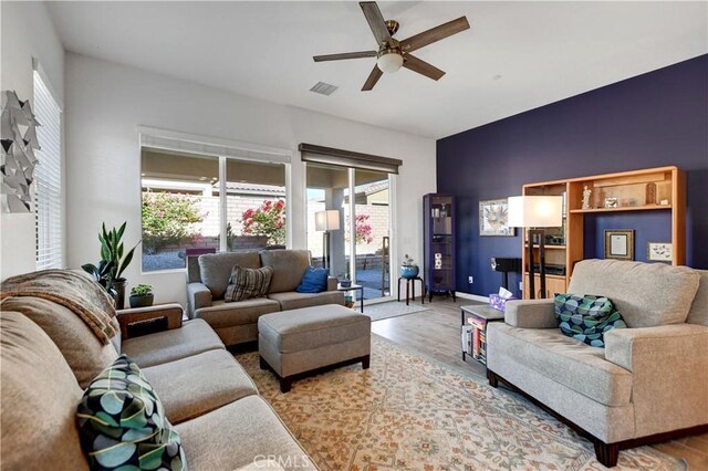 living room featuring ceiling fan, wood-type flooring, and a wealth of natural light